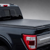 Access Lorado ultra-low-profile soft roll-up tonneau cover on a black Ford truck in a dark gray showroom